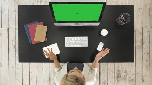 Pessoa fazendo videoconferência no computador. Tela verde