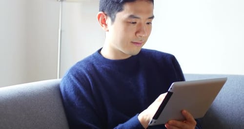 Young Adult Using Tablet on Couch Indoors