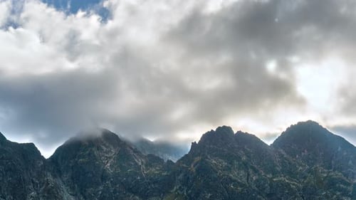 Dark Clouds Moving Fast over Rocky Alpine Mountain Peak