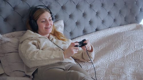 Woman Enjoying Video Game on Bed with Headphones