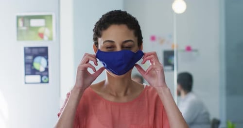 Portrait of caucasian woman adjusting her face mask at modern office