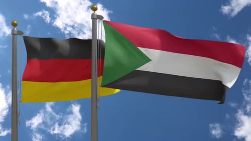 Germany and Sudan Flags Waving Against Blue Sky