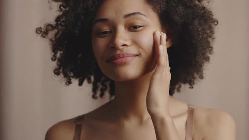Woman Applying Cream to Face in Close Up