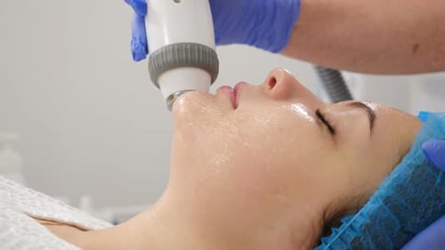 Non-surgical Face Lifting in Beauty Clinic. Cosmetologist Moves Manipulator on Client Face