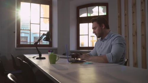 Man Typing on Laptop in Bright Office