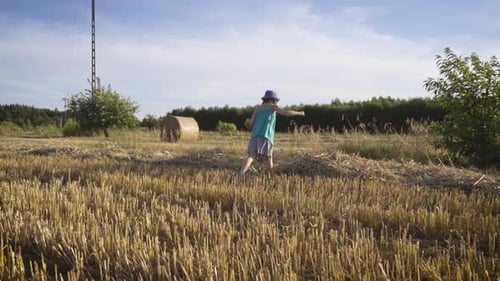 Cute Little Girl Walks Through the Mown Rye Field