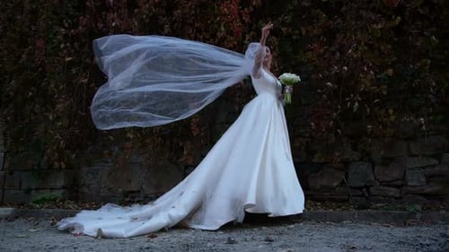 Bride Posing with Veil and Bouquet Outdoors
