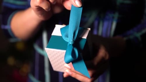 Woman Unties Turquoise Ribbon on Small Gift Box