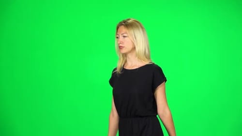 Pensive Girl Is Walking on a Green Screen at Studio. Slow Motion