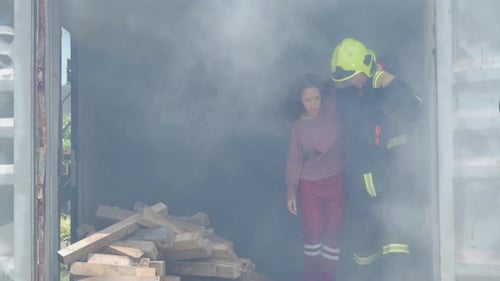 An emergency rescue team helping a young victim woman, saving her life from hot burning fire