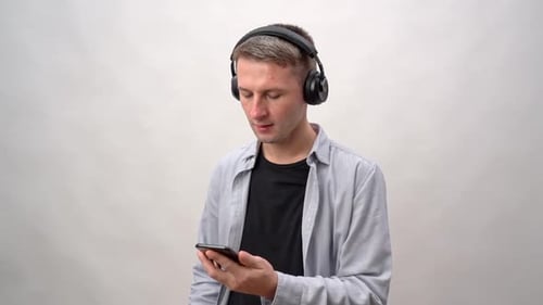 Young Adult Listens with Headphones and Smartphone