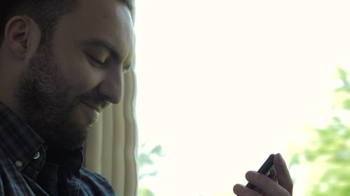 Young Adult Man Uses Mobile Device Indoors