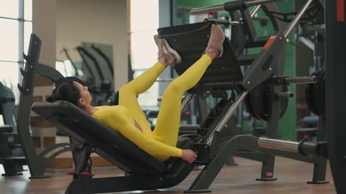 Hispanic Woman Using A Press Machine In A Fitness Club