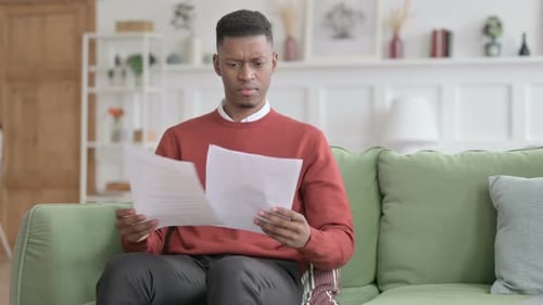 Young Adult Reading Paperwork on Couch