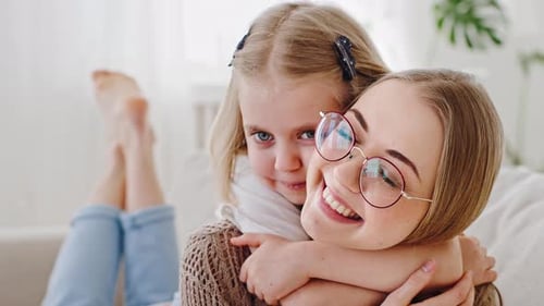 Child Embracing a Smiling Woman on Sofa