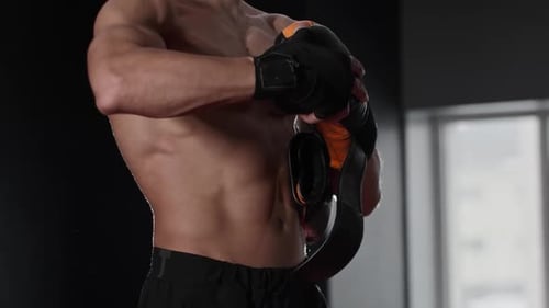 Muscular Adult Puts On Boxing Gloves in Gym