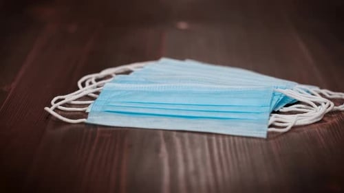 Pile of Disposable Face Masks on Wooden Surface