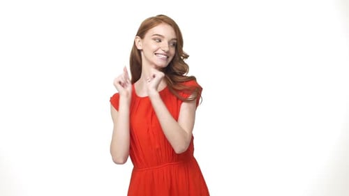 Retrato de mujer joven caucásica de primer plano con vestido naranja tímida bailando sobre fondo blanco aislado