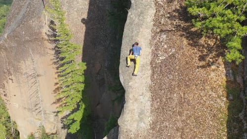 Luftaufnahme eines jungen Mannes, der vorsichtig ohne Sicherheitsnetz auf eine Felswand klettert