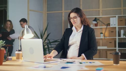 Une femme d'affaires enceinte prospère travaille avec des collègues