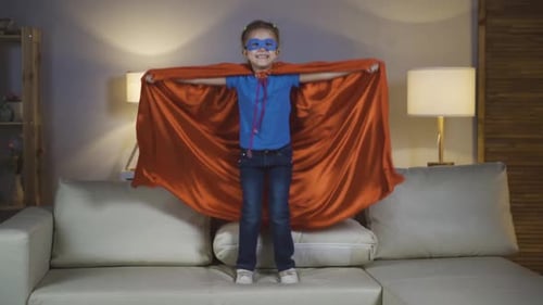 Smiling Child Wearing Superhero Cape on Couch