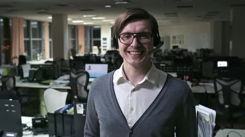 Fröhlicher Callcenter-Mitarbeiter lächelt vor Kamera