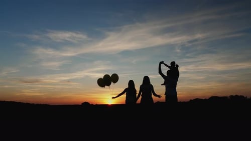 Family Silhouetted With Balloons at Sunset
