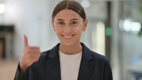 Young Woman Gives Thumbs Up in Office Setting