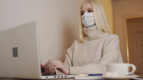 Young Adult Working on Laptop with Surgical Mask