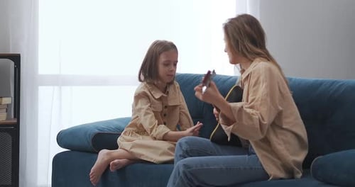 Woman Plays Ukelele with Child on Couch