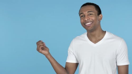 African Man Showing Product at Side, Blue Background