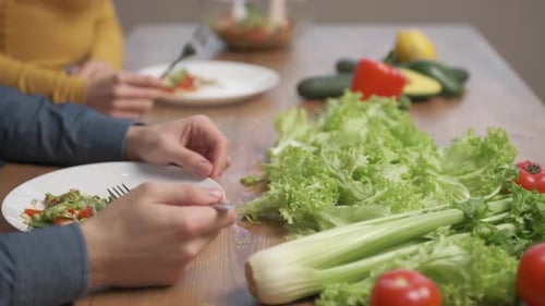 Close up food in dish and hand of people. Couple eating salad