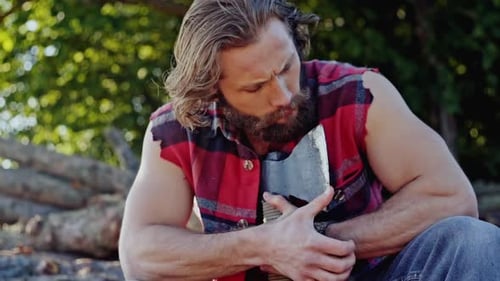 Muscular Lumberman Sitting with Axe