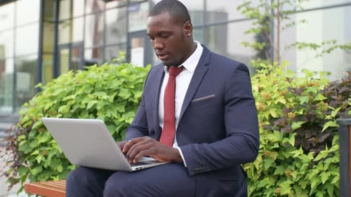 Young Adult Using Laptop on Bench Outdoors