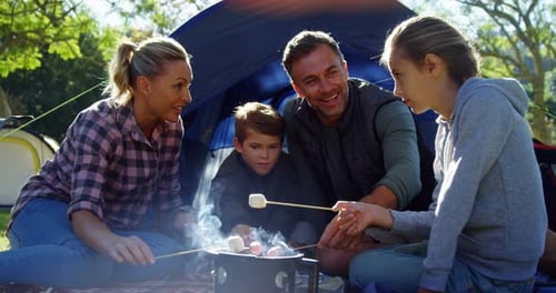 Family roasting marshmallows outside the tent