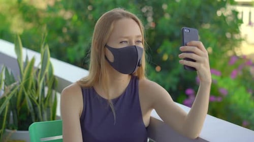 Young Adult Video Chatting with a Mask Outdoors