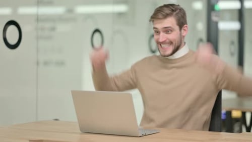 Creative Young Man with Laptop Celebrating in Office