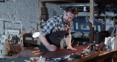 Male Artisan Rolling Leather in Workshop