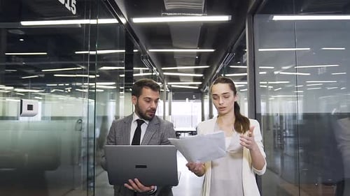 Geschäftsmann und Geschäftsfrau gehen durch die Long Glass Office Hall