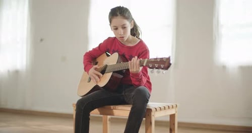 Young Girl Plays Acoustic Guitar in Bright Room