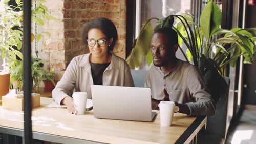 Black Man and Woman Discussing Business Project on Laptop in Cafe