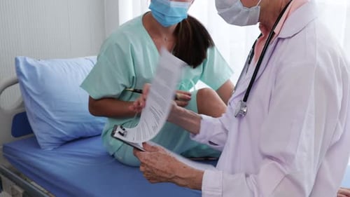 Doctor Reviews Chart with Patient in Hospital Room