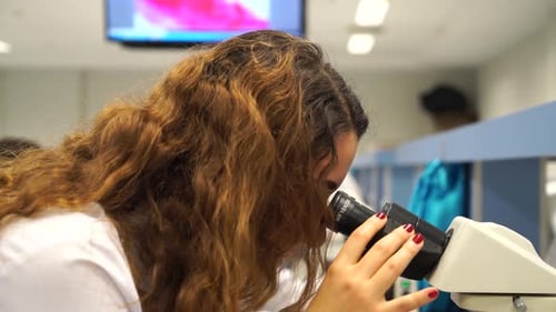 Focused Young Researchers Using Microscopes in Lab