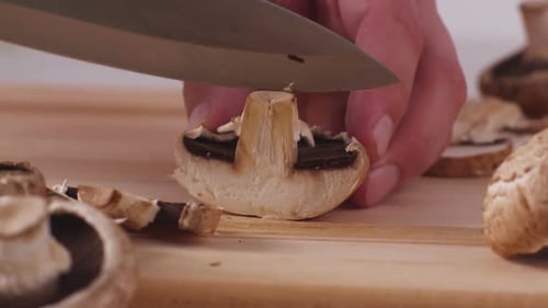 Close Up of Hand Slicing Mushrooms on Cutting Board