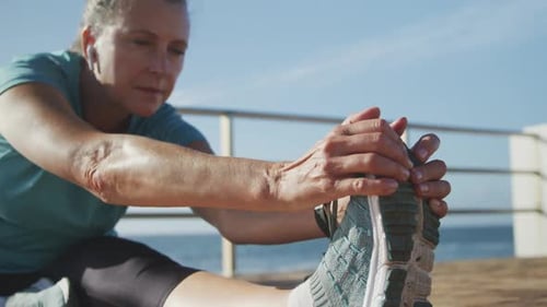 Senior woman stretching her legs on a promenade