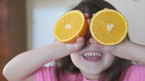Smiling Girl Playing with Orange Halves