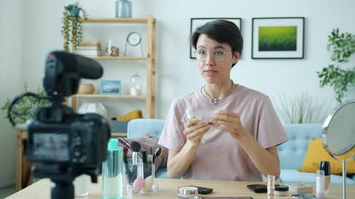 Bloguero creativo graba Vídeo para un vlog en línea con productos de maquillaje y hablando