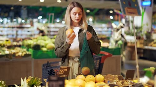 Woman Selecting Grapefruit at a Grocery Store
