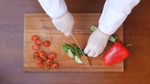 Hands Slicing Cucumber on Cutting Board