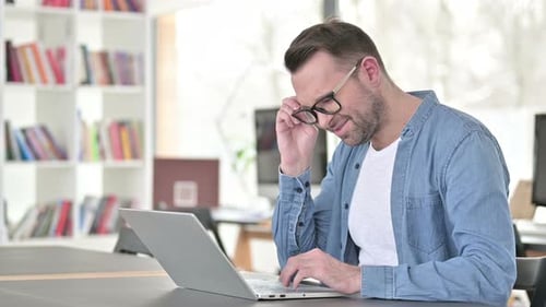 Man Using Laptop Removes Glasses Rubs Eyes